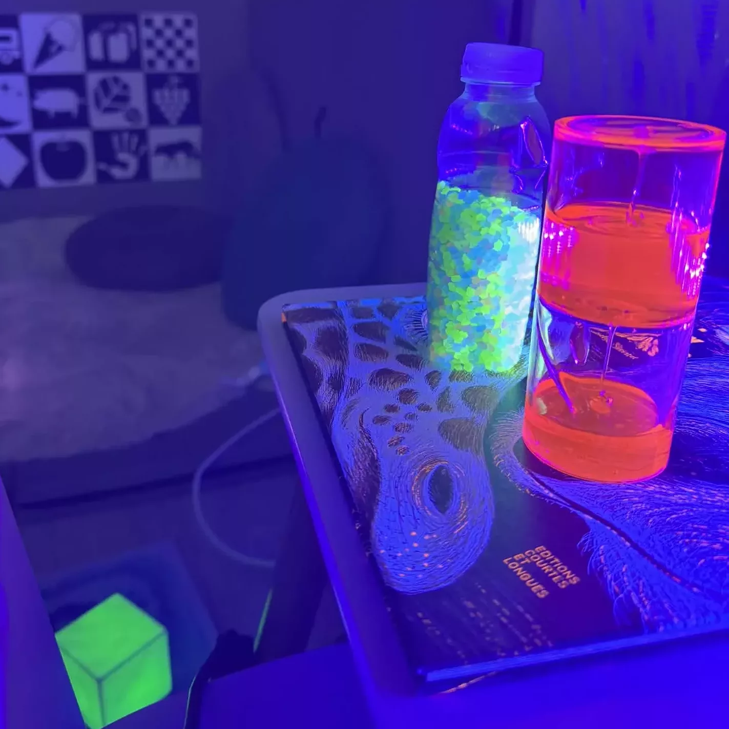 Quatre jeunes enfants découvrent une ambiance sensorielle apaisante autour d'une lampe sensorielle lumineuse, dans une salle décorée de guirlandes LED multicolores suspendues. Une expérience sensorielle idéale pour l'éveil, la relaxation et la stimulation des sens chez les tout-petits.